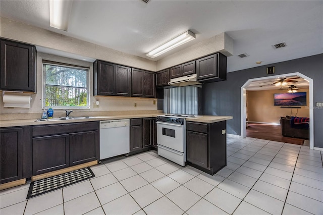 kitchen with sink, light tile patterned floors, ceiling fan, dark brown cabinets, and white appliances