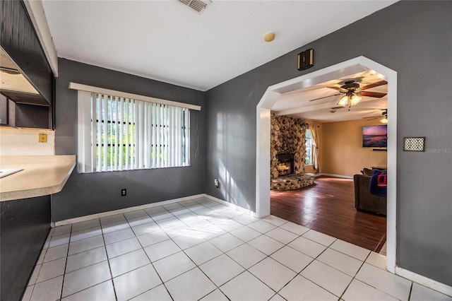 unfurnished dining area with a fireplace, ceiling fan, and light hardwood / wood-style flooring