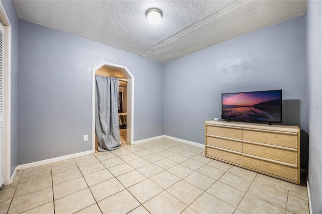 unfurnished bedroom with a textured ceiling and light tile patterned flooring