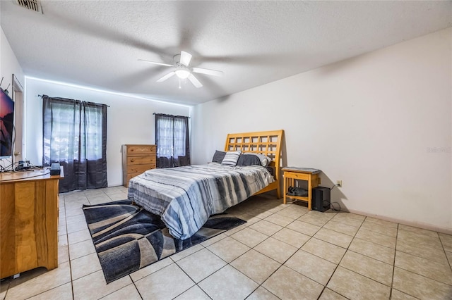 bedroom featuring ceiling fan, a textured ceiling, and light tile patterned floors