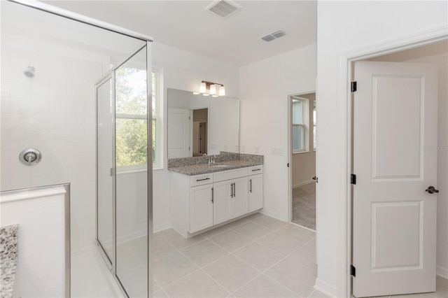 bathroom featuring a shower with shower door, vanity, and tile patterned flooring