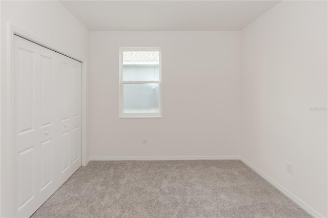 unfurnished bedroom with light colored carpet and a closet