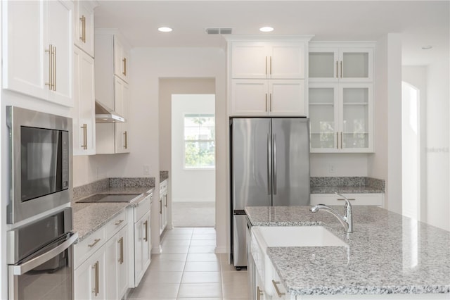 5648 Green Arrow Pl, Sanford, FL 32773 - kitchen with appliances with stainless steel finishes, white cabinets, glass insert cabinets, an island with sink, and recessed lighting