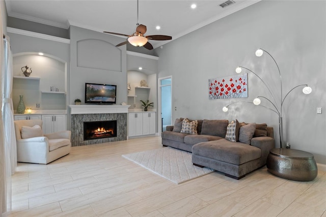 living room featuring a towering ceiling, ceiling fan, and crown molding