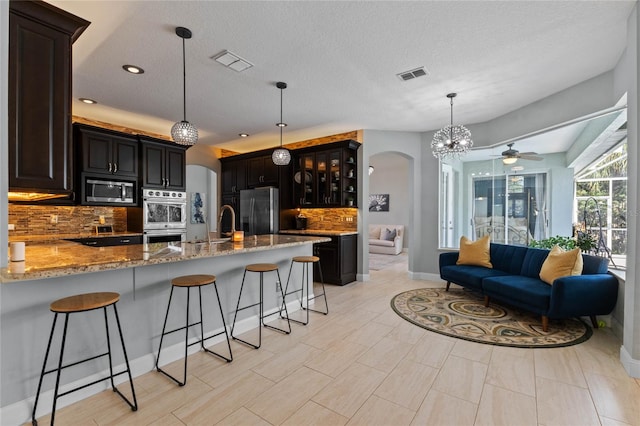 kitchen featuring pendant lighting, decorative backsplash, ceiling fan, appliances with stainless steel finishes, and kitchen peninsula