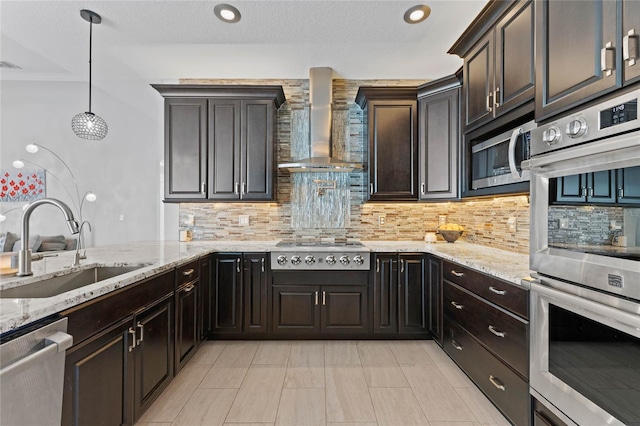 kitchen with sink, hanging light fixtures, stainless steel appliances, wall chimney range hood, and backsplash