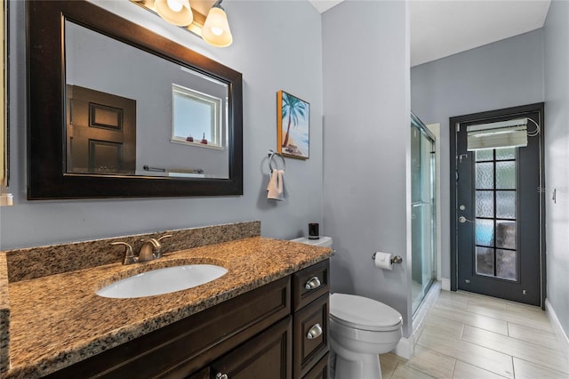 bathroom featuring tile patterned floors, vanity, toilet, and a shower with shower door