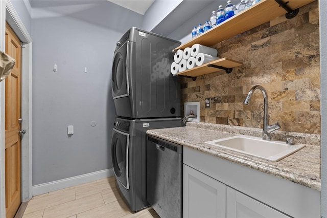 kitchen with decorative backsplash, light stone counters, sink, dishwasher, and stacked washer / drying machine