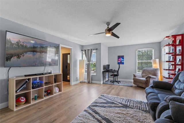 living room with ceiling fan, a textured ceiling, and light hardwood / wood-style flooring