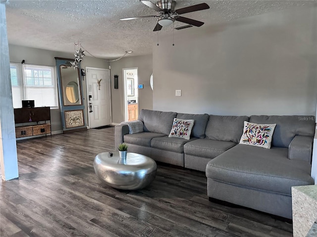 living room featuring dark hardwood / wood-style flooring, ceiling fan, and a textured ceiling