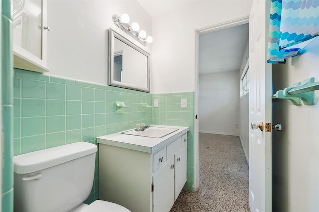 bathroom featuring toilet, vanity, and tile walls