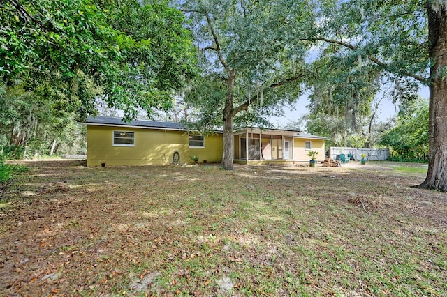 back of house featuring a lawn and a sunroom