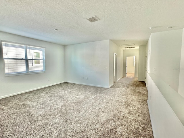 unfurnished room featuring a textured ceiling and light carpet