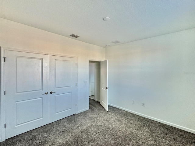 unfurnished bedroom featuring dark colored carpet, a textured ceiling, and a closet