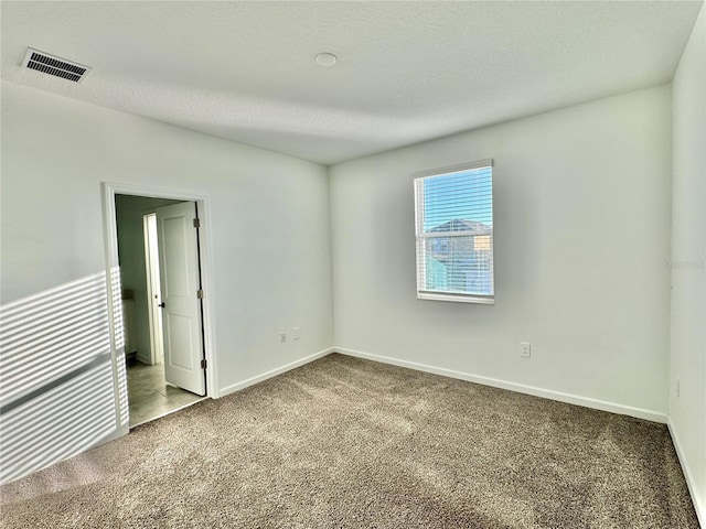 carpeted spare room featuring a textured ceiling