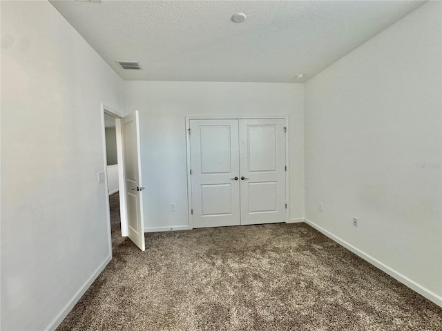 unfurnished bedroom with a textured ceiling, carpet floors, and a closet