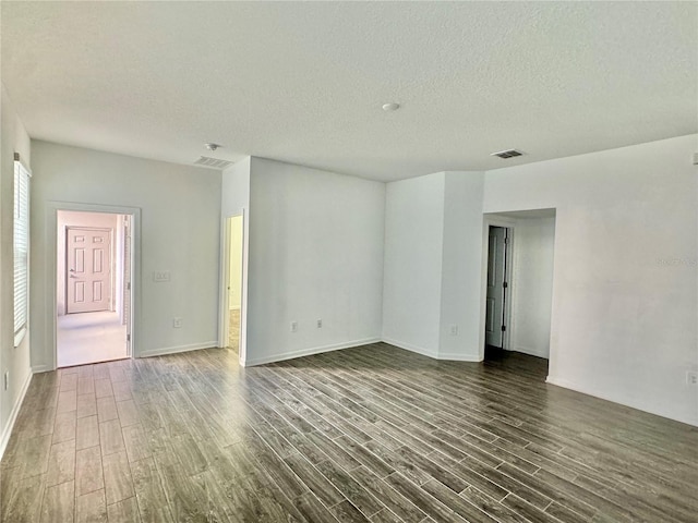 unfurnished room with a textured ceiling and dark wood-type flooring