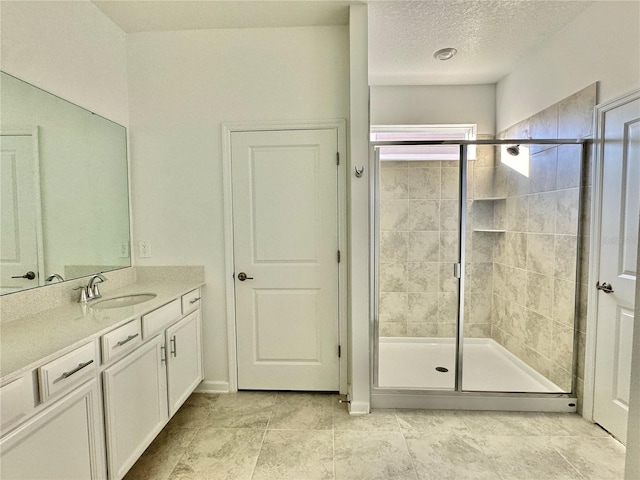 bathroom featuring vanity, an enclosed shower, and a textured ceiling