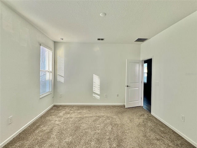 carpeted spare room featuring a textured ceiling