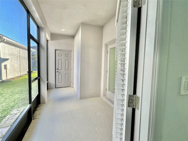 hall with light colored carpet and a textured ceiling