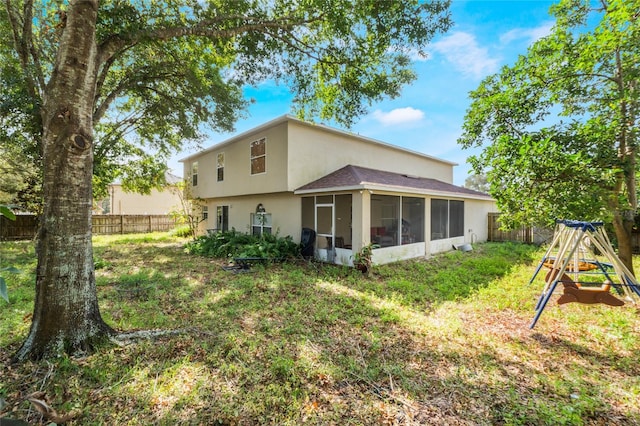 rear view of house featuring a lawn and a sunroom