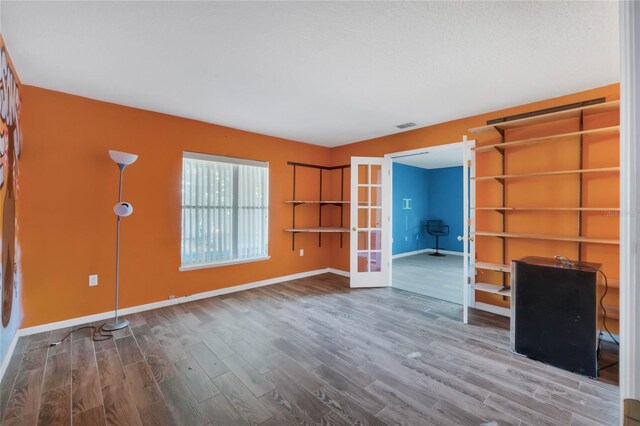 unfurnished living room with hardwood / wood-style floors and french doors