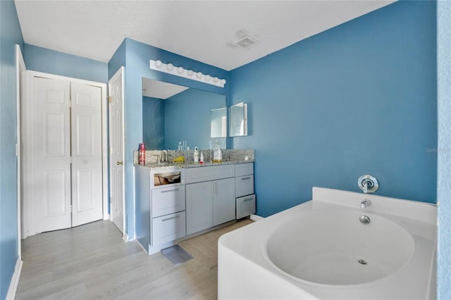 bathroom featuring a washtub, vanity, and hardwood / wood-style flooring