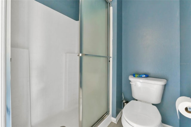 bathroom featuring toilet and a shower with shower door