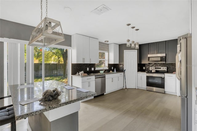 kitchen featuring pendant lighting, backsplash, stainless steel appliances, and a healthy amount of sunlight