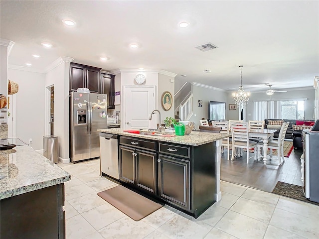 kitchen featuring a center island with sink, ceiling fan with notable chandelier, hanging light fixtures, ornamental molding, and appliances with stainless steel finishes