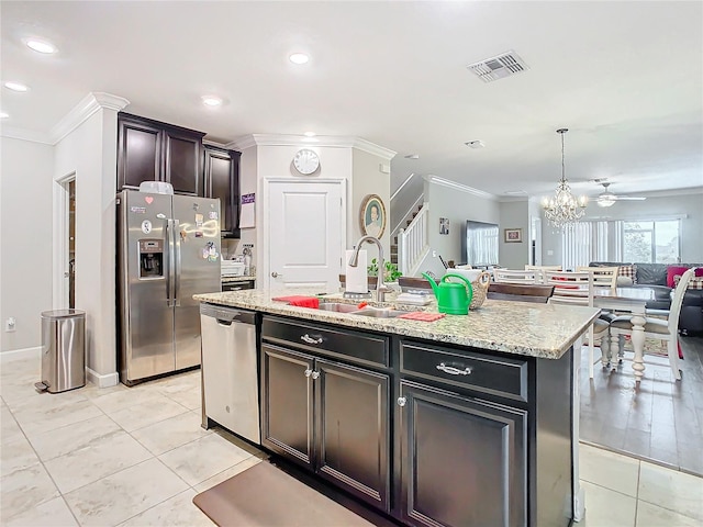 kitchen featuring pendant lighting, sink, ornamental molding, an island with sink, and stainless steel appliances