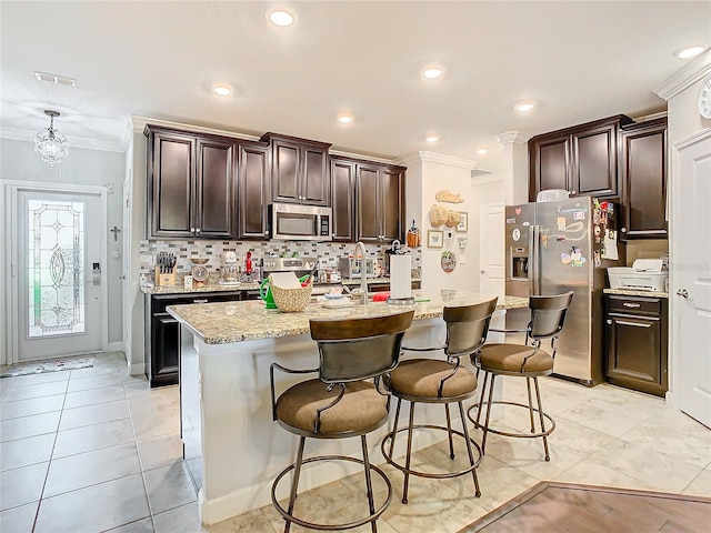 kitchen featuring a center island with sink, ornamental molding, stainless steel appliances, and tasteful backsplash