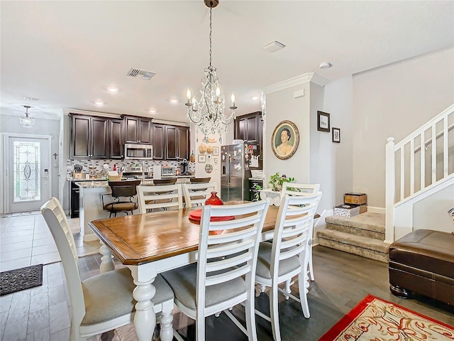 dining room with light wood-type flooring, crown molding, and a chandelier