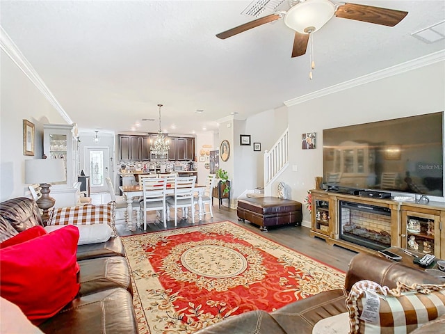 living room featuring ceiling fan with notable chandelier, light wood-type flooring, and crown molding