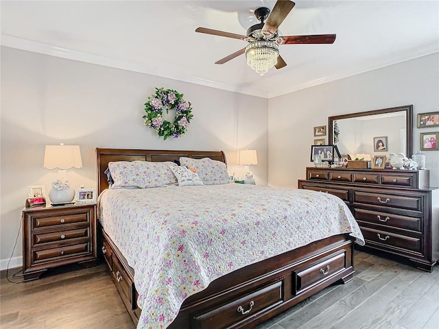 bedroom with hardwood / wood-style floors, ceiling fan, and crown molding