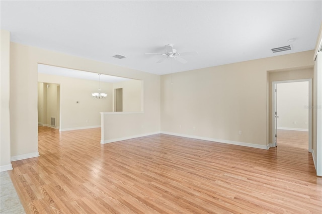 unfurnished room with ceiling fan with notable chandelier and light hardwood / wood-style flooring