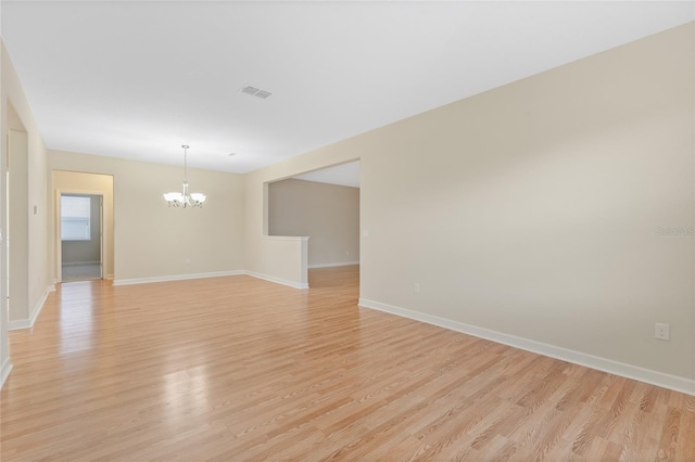 empty room with light hardwood / wood-style flooring and a notable chandelier