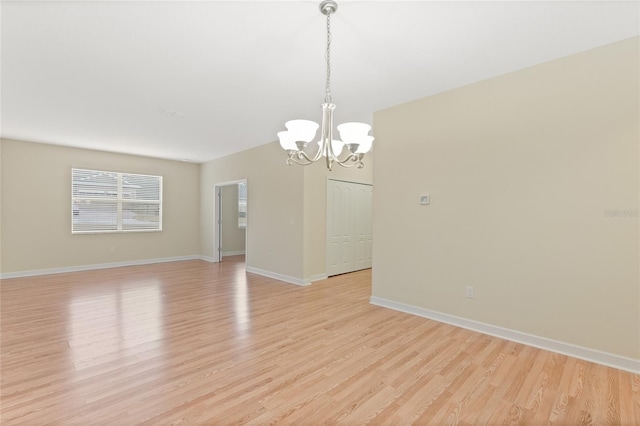 empty room featuring a chandelier and light wood-type flooring