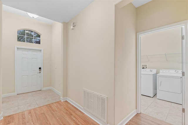 foyer with washing machine and dryer and light hardwood / wood-style floors