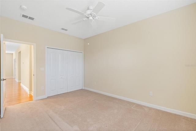 unfurnished bedroom with light colored carpet, ceiling fan, and a closet