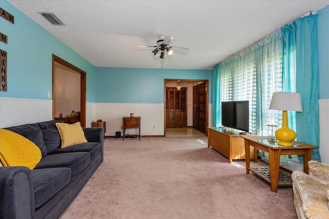 living room featuring carpet flooring, ceiling fan, and a textured ceiling