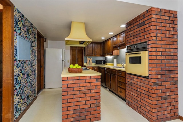 kitchen with appliances with stainless steel finishes, custom exhaust hood, dark brown cabinets, sink, and a kitchen island