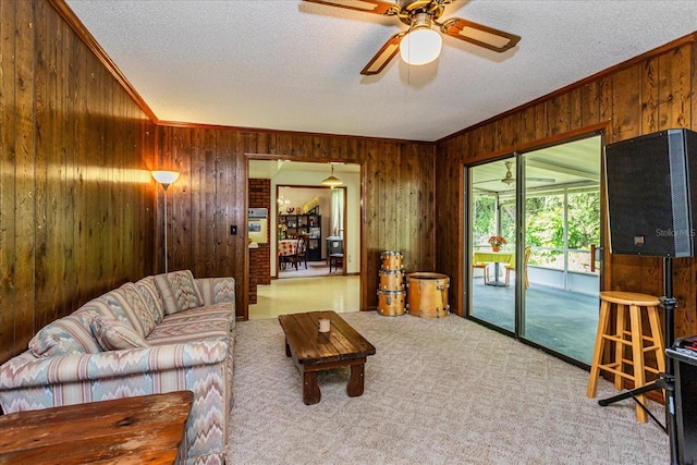 carpeted living room with wood walls, ornamental molding, and a textured ceiling