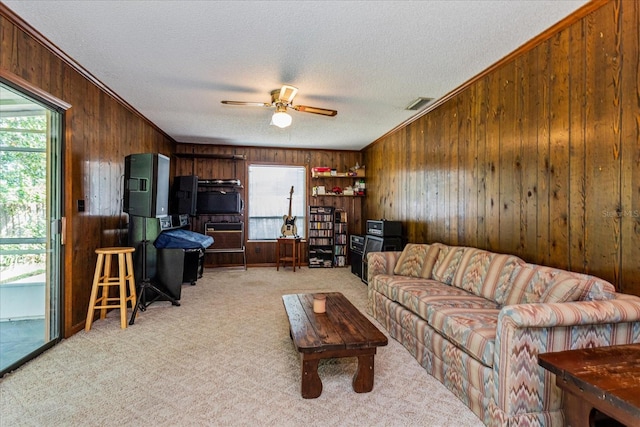 living room featuring wood walls, crown molding, and ceiling fan