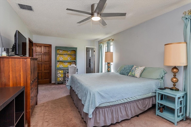 bedroom featuring ceiling fan, light colored carpet, and a textured ceiling