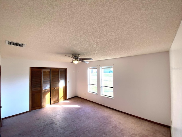 unfurnished bedroom with carpet, ceiling fan, a textured ceiling, and a closet