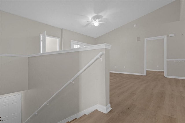 corridor featuring lofted ceiling, wood finished floors, an upstairs landing, and baseboards