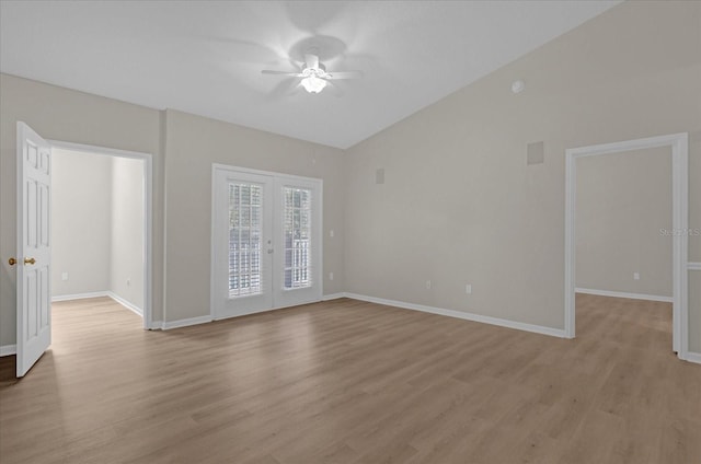 spare room featuring lofted ceiling, light wood finished floors, baseboards, and french doors