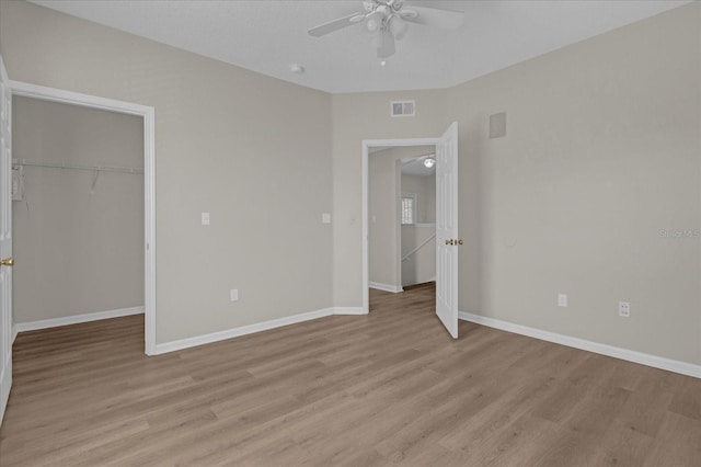 unfurnished bedroom featuring a spacious closet, a closet, light wood-type flooring, and visible vents