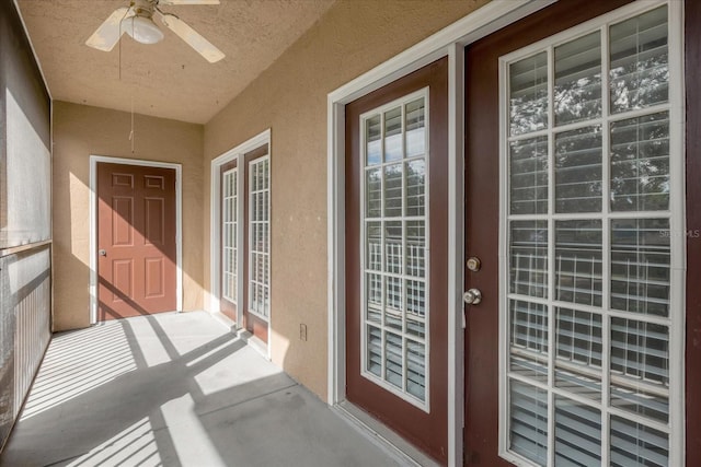 view of exterior entry featuring a ceiling fan and stucco siding